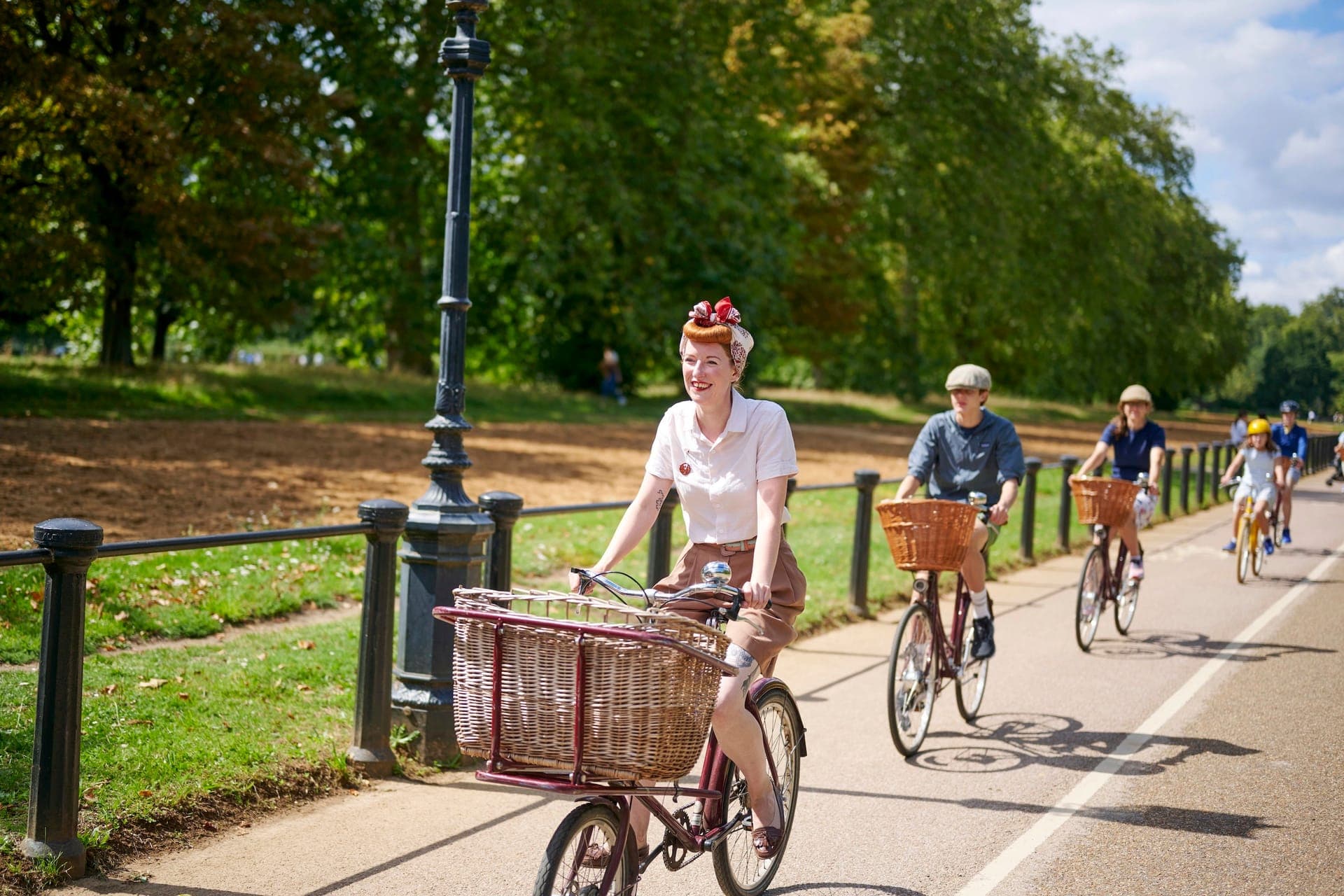 A family cycles through Hyde Park on vintage bicycles
