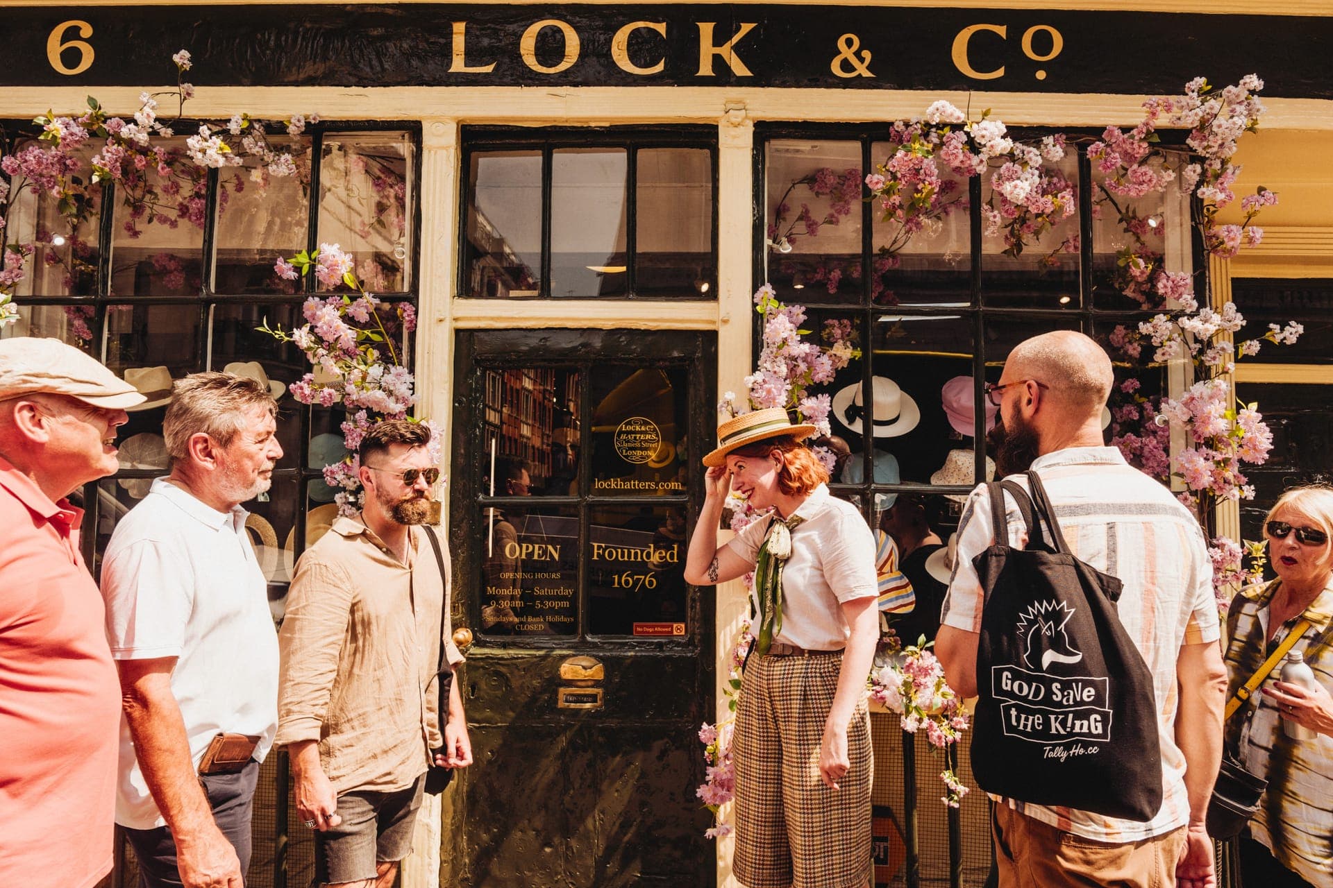 A tour group stops outside of Lock & Co. Hatters
