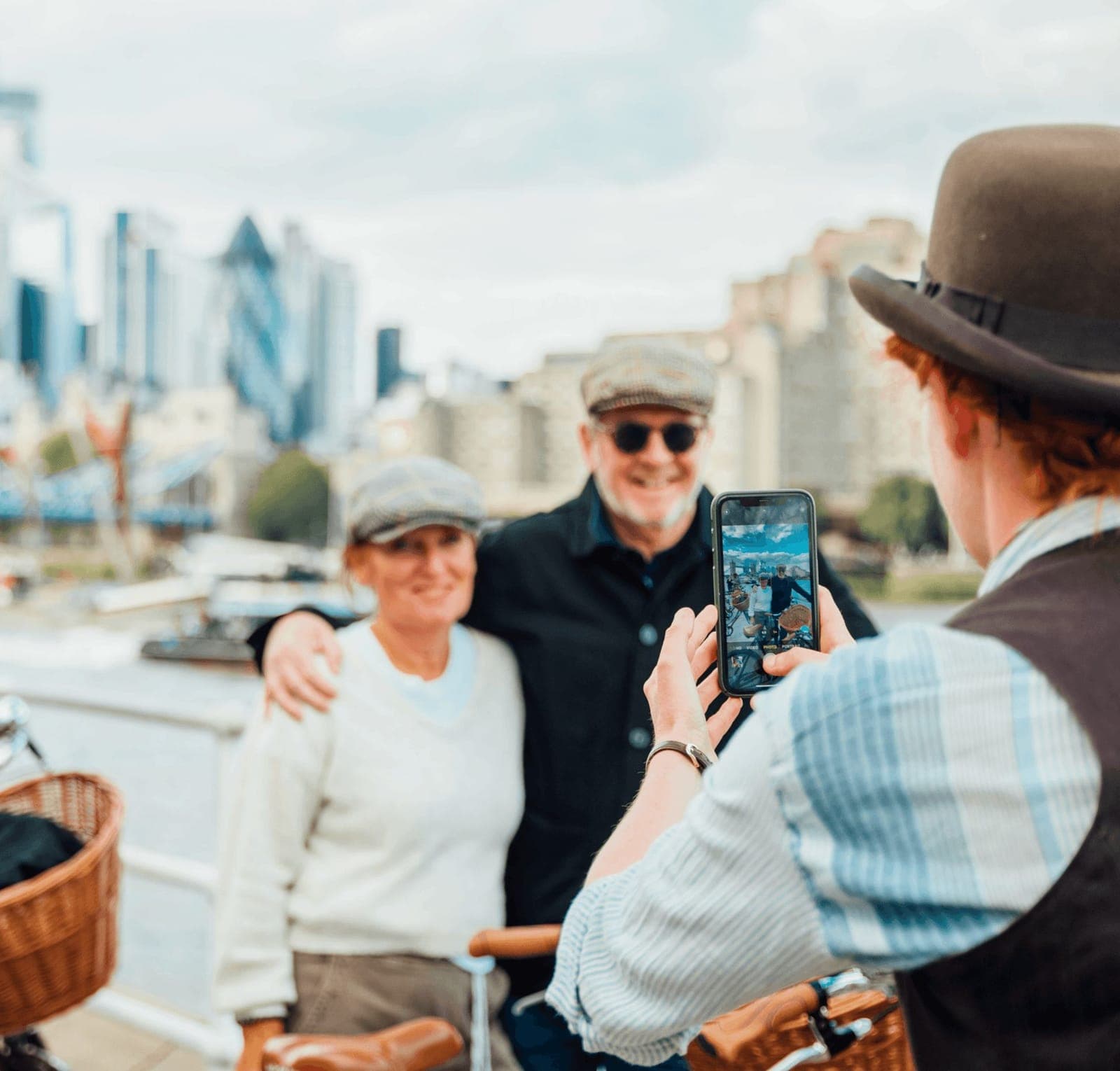 A couple wearing tweed caps pose for a photograph with Tower Bridge on a Tally Ho bike tour
