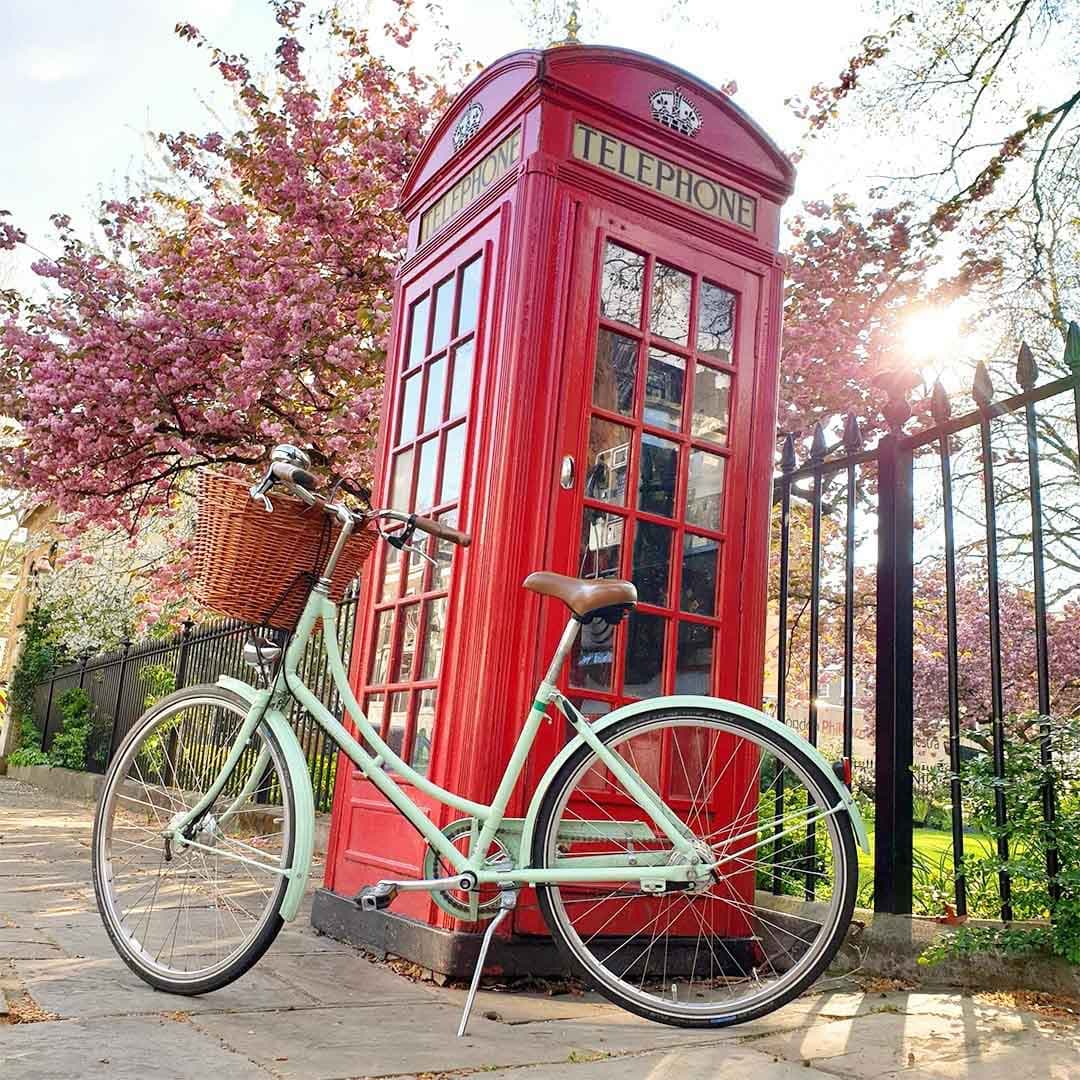 A vintage Pashley bicycle in front of a bright red telephone box