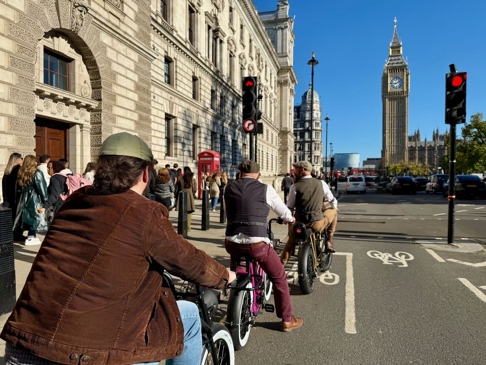 Riders on retro eBikes waiting at a red light in a Westminster cycle lane, with Big Ben ahead