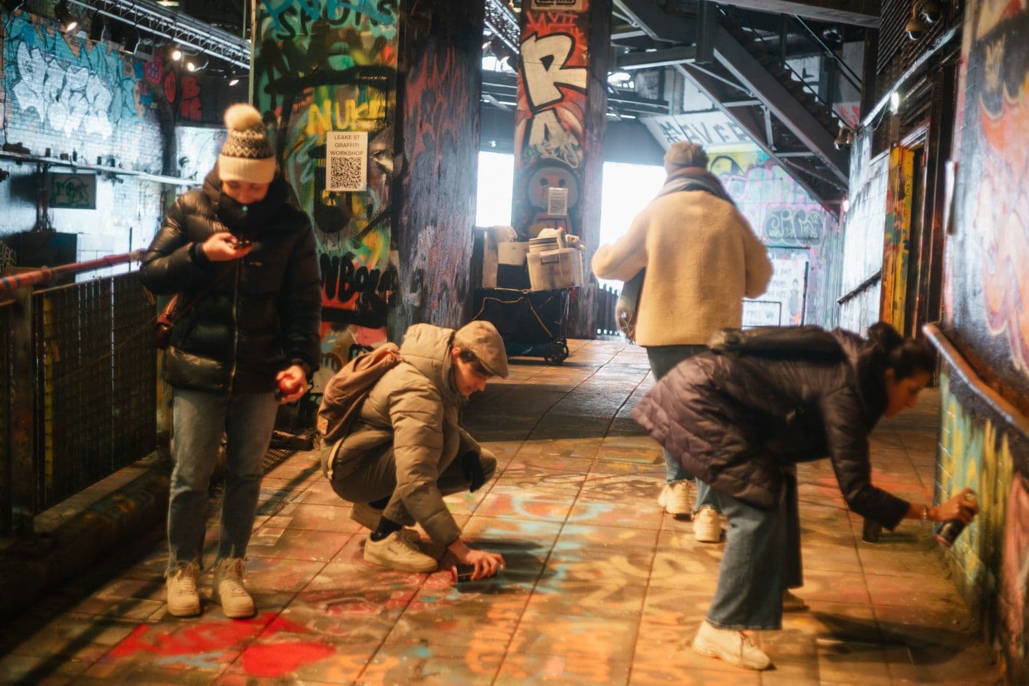 People trying out spray paint in the Leake Street graffiti tunnel