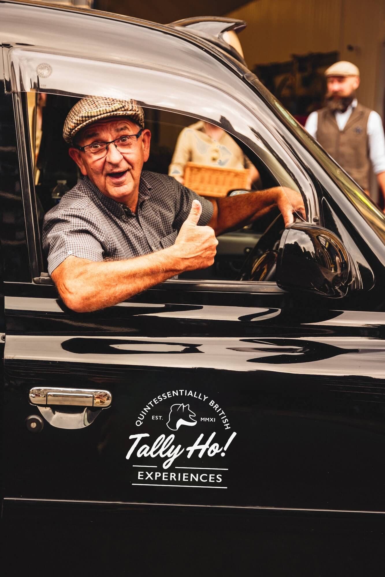 Tally Ho driver-guide leaning out of a London black cab with a thumbs up